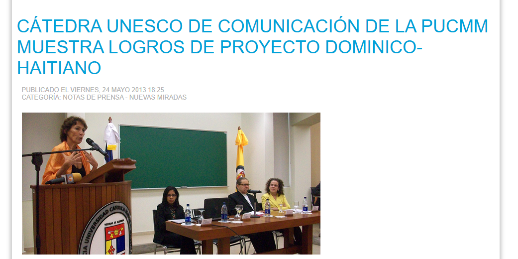 image 1 Fotografía de un panel académico en la PUCMM: una expositora habla desde un podio mientras otros cuatro panelistas están sentados en una mesa frente al público. La imagen acompaña la nota titulada ‘Cátedra UNESCO de Comunicación de la PUCMM muestra logros de proyecto dominico-haitiano’, publicada en mayo de 2013.